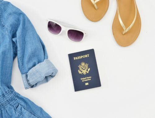 Road trip gear, including a passport, a dress, shades, and flip flops